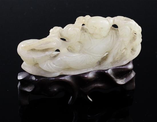 A Chinese pale celadon jade carving of a boy seated on a pine raft, 18th/19th century, 7.1cm, rosewood stand